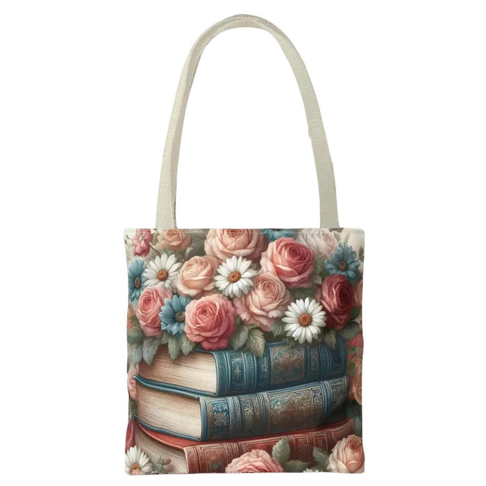 A tote bag with a floral design featuring a stack of books with roses and daisies on top.