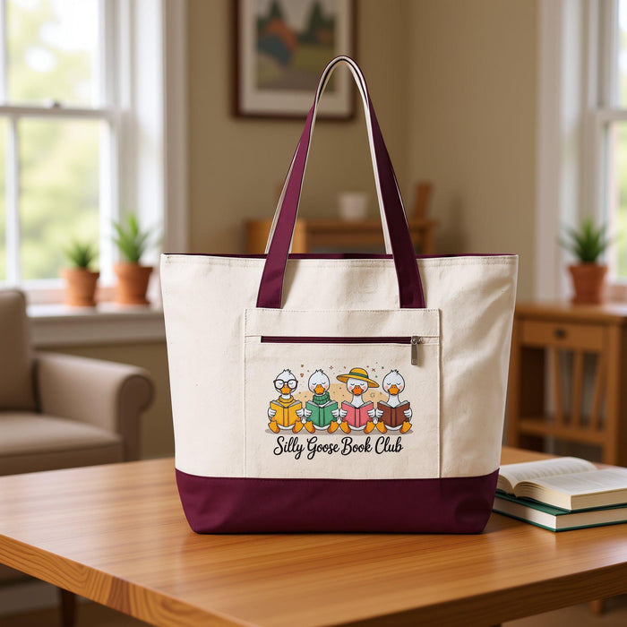 A tote bag and a travel mug with a design featuring cartoon ducks and the text "Silly Goose Book Club" are displayed on a wooden table.