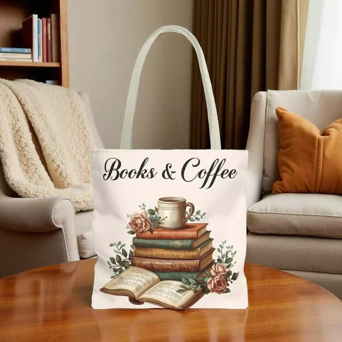 A white tote bag with a printed design of a stack of books and a cup of coffee, placed on a wooden table in a living room setting.