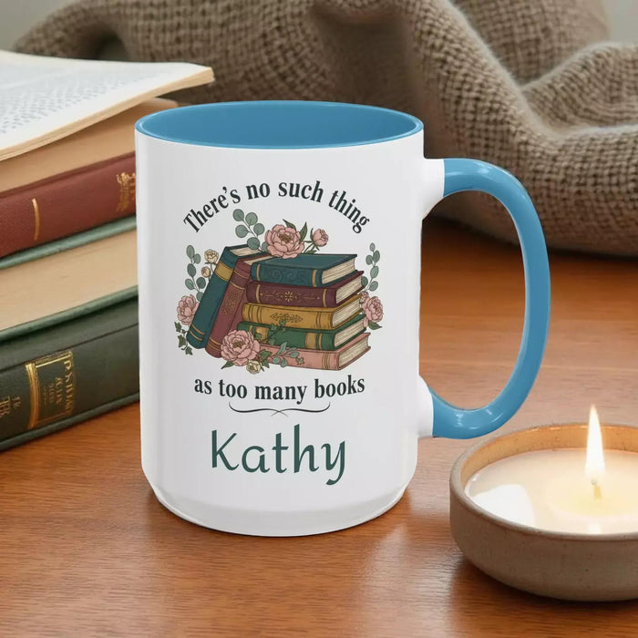 a tote bag and a mug with a printed design, including a stack of books and the text "There's no such thing as too many books" and "There's no such thing as too many books" on them. The items are placed on a table with some greenery, and there is a text overlay that reads "Tote Bag & Mug Gift Set" and "Buy the Tote & add the Mug".