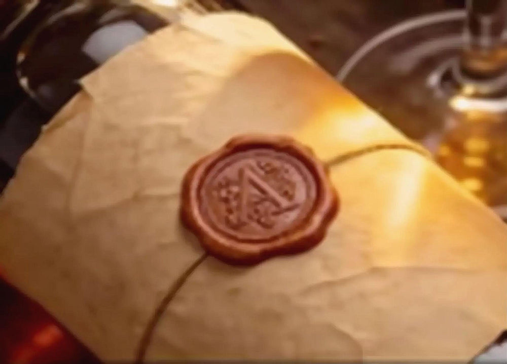 A close-up image of a wax seal or wax stamp on a piece of paper, with a glass of wine visible in the background.