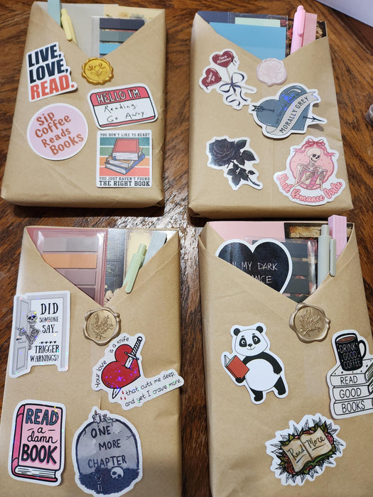 two wrapped books with red ribbons, along with various items such as tea bags, a mug, and a scroll. The text overlay reads "Blind Date with a Book" and "BONUS Extras".