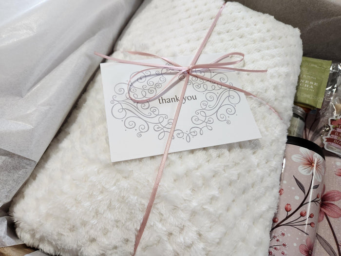 A box containing various items, including a book, snacks, candles, and other miscellaneous items, all wrapped in brown paper and tied with twine.