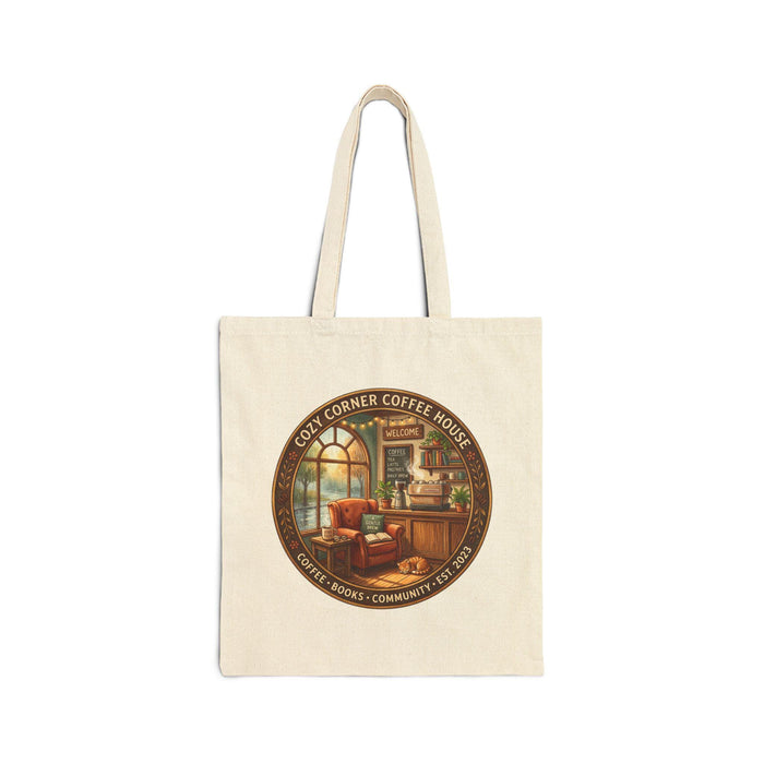 A cozy corner coffee house gift set, including a tote bag and a mug, is displayed on a table with various items such as books, a cup of coffee, and a pastry.
