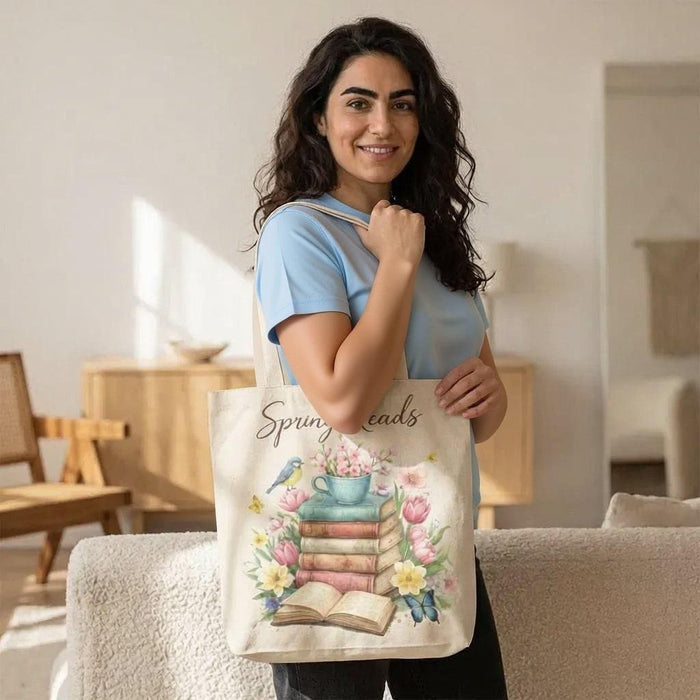 A beige tote bag with a floral design and a stack of colorful books.