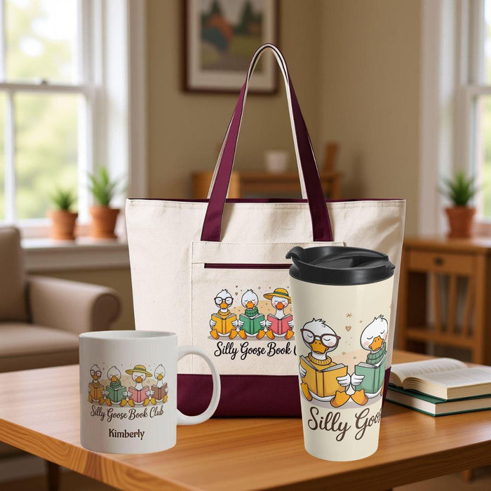 A tote bag and a travel mug with a design featuring cartoon ducks and the text "Silly Goose Book Club" are displayed on a wooden table.