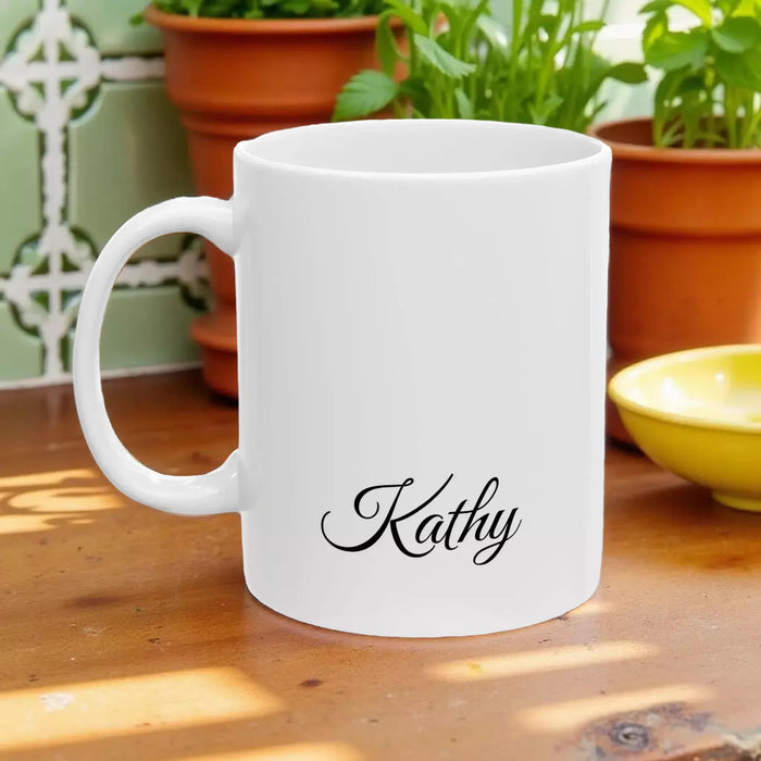 A white tote bag with a printed design of a stack of books and a cup of coffee, placed on a wooden table in a living room setting.