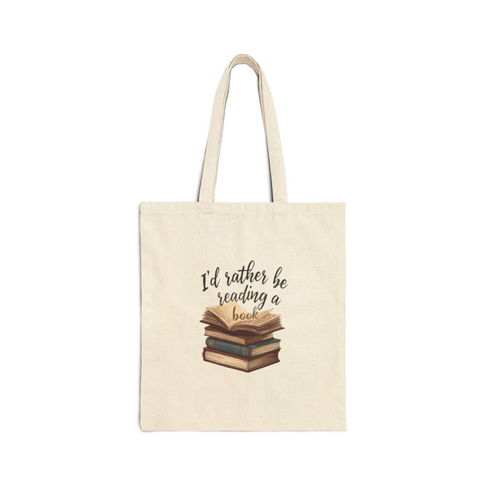 A beige tote bag with a printed design on it, depicting a stack of books. The text on the bag reads "I'd rather be reading a book".