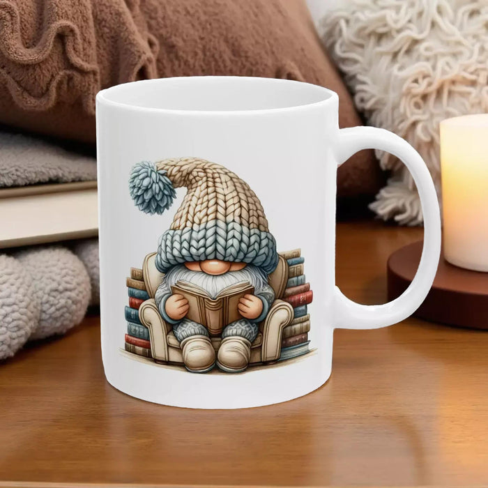a tote bag and a mug with a gnome sitting on a stack of books, both with a knitted hat on.