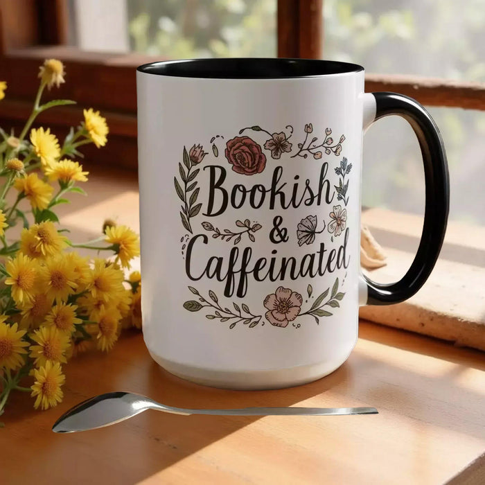 A white tote bag with a floral design and a purple handle, along with a white mug with a floral design and a purple handle, both sitting on a beige surface.